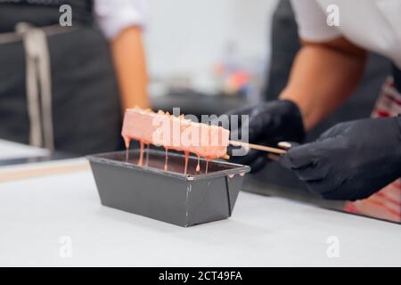 Close-up of chef hands preparing cakes and desserts covered with chocolate glaze Stock Photo