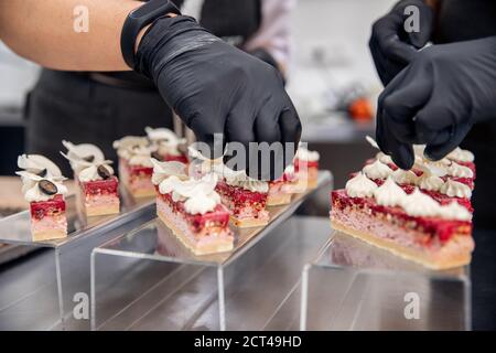 Close-up of chef hands preparing cakes and desserts covered with chocolate glaze Stock Photo