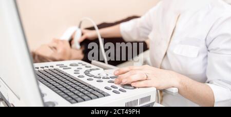 Doctor conducts ultrasound examination of woman thyroid gland in clinic, lack of iodine Stock Photo