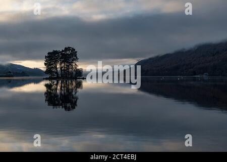 Lone trees on an island reflecting in Loch Tay Lake at sunset with dramatic sunset sky reflections, Kenmore, Perthshire, Highlands of Scotland, United Kingdom, Europe Stock Photo