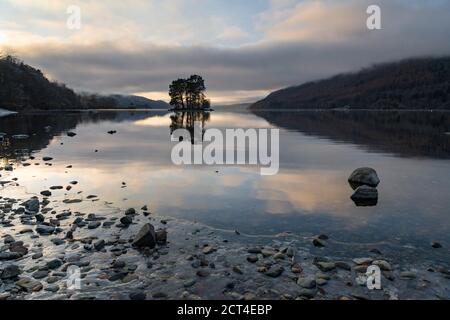 Lone trees on an island reflecting in Loch Tay Lake at sunset with dramatic sunset sky reflections, Kenmore, Perthshire, Highlands of Scotland, United Kingdom, Europe Stock Photo