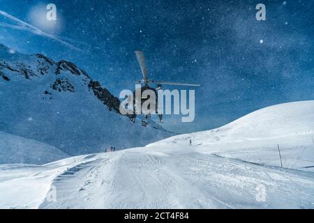 Mountain rescue team helicopter rescuing an injured skier after having a skiing accident in the Alps mountains, at Avoriaz, France, Europe Stock Photo
