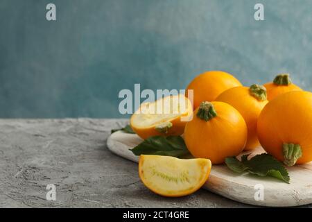 Board with round zucchini and leaves on gray background Stock Photo