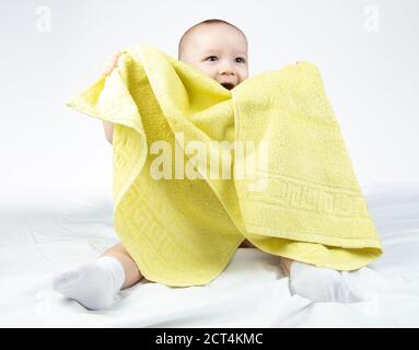 Photo of smiling eleven-month-old baby with yellow towel Stock Photo