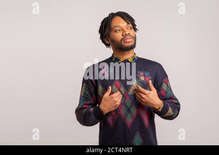 Self confident egoistic guy with dreadlocks pointing hands on himself with arrogant face, proud of start up. Indoor studio shot isolated on gray backg Stock Photo