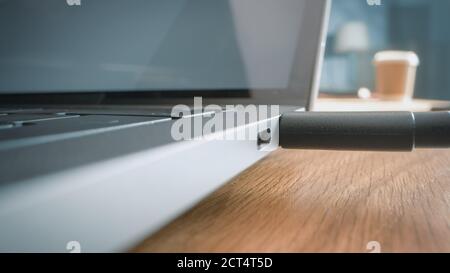 Close-up Macro Shot: Laptop on the Desk, Person Inserts USB-C Cable Adapter into Computer Port. Stock Photo