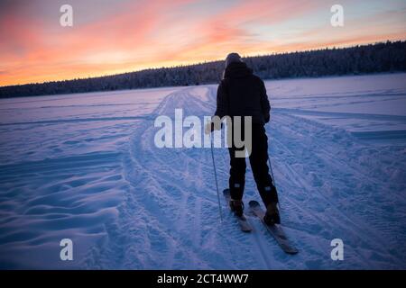 Skiing on the frozen lake at Torassieppi at sunset, Lapland, Finland Stock Photo