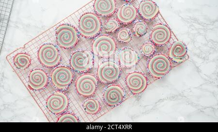Step by step. Flat lay. Cooling freshly baked bake red, white, and blue pinwheel sugar cookies on a cooling rack. Stock Photo