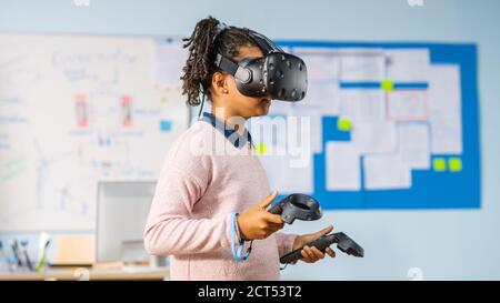 Elementary School Computer Science Class: Cute Girl Wearing Augmented Reality Headset and Using Controllers Learns Lessons in Virtual Reality Excited Stock Photo