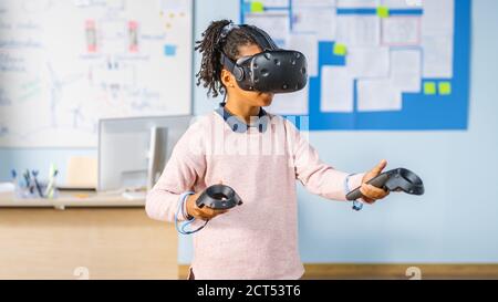 Elementary School Computer Science Class: Cute Girl Wearing Augmented Reality Headset and Using Controllers Learns Lessons in Virtual Reality Excited Stock Photo