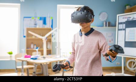 Elementary School Computer Science Class: Cute Girl Wearing Augmented Reality Headset and Using Controllers Learns Lessons in Virtual Reality Excited Stock Photo