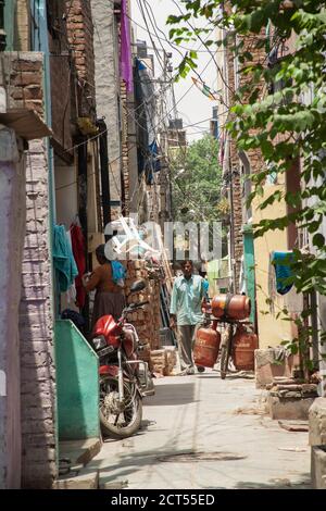 A man in a cluttered alleyway in the Delhi slums, India Stock Photo