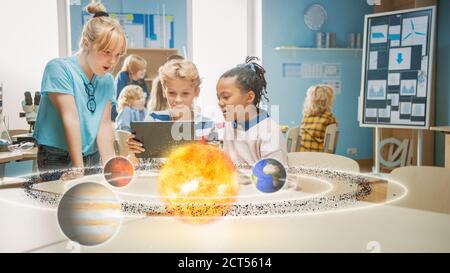 Three Diverse School Children in Science Class Use Digital Tablet Computer with Augmented Reality Software, Looking at Educational 3D Animation Of Stock Photo