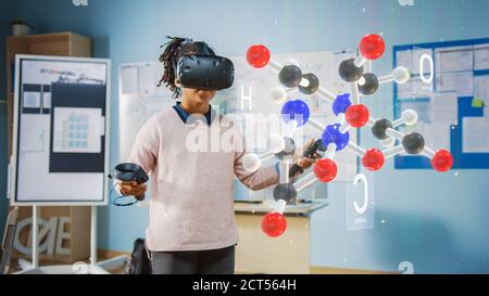 Cute Girl Wearing Augmented Reality Headset and Using Controllers Interacts with 3D Molecule. Futuristic School Science Class for Children Learning in Stock Photo