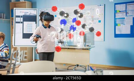 Cute Girl Wearing Augmented Reality Headset and Using Controllers Interacts with 3D Molecule. Futuristic School Science Class for Children Learning in