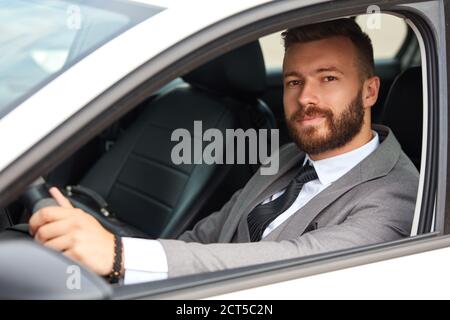 handsome caucasian businessman sits inside of representative luxurious car, confident male in formal wear Stock Photo
