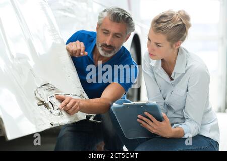 man and woman talking about fixing a car body Stock Photo