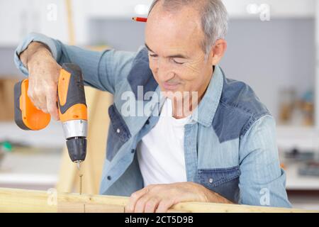 senior man using a power drill Stock Photo