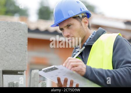 handsome builder writing on clipboard Stock Photo