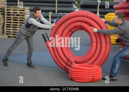 happy workers moving heavy pipes outdoors Stock Photo