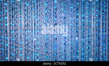 Blue and turquoise background of LED flashing, blinking and flickering bulbs. Disco and holiday illuminated neon shiny backdrop. Abstract wall decorat Stock Photo