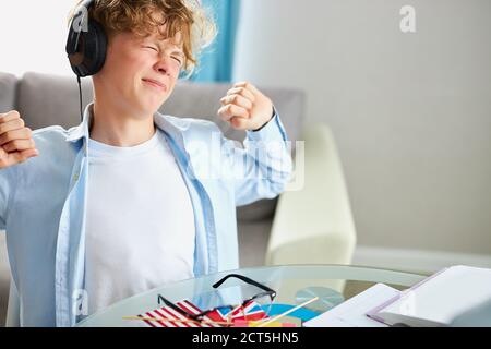 young boy is stretching while doing homework at home, tired to study online Stock Photo