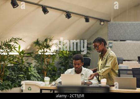 Portrait of two African-American people working in modern open space office, focus on female manager instructing trainee or colleague, copy space Stock Photo