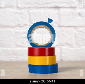 stack of colorful insulating tape on white brick wall background, close up Stock Photo