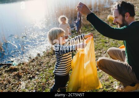 Father with small kids collecting rubbish outdoors in nature, plogging concept. Stock Photo