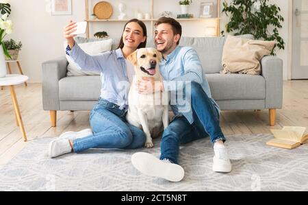 Young couple taking selfportrait with dog at home Stock Photo