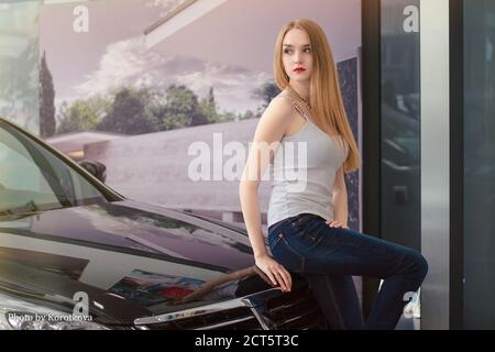 Buying new car. Smiling young woman being glad about her newly-bought car. Stock Photo