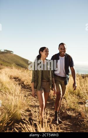 Smiling couple on a hiking trip on a sunny day. Portrait of a couple walking together on a hiking trail. Stock Photo