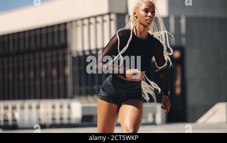 Sporty woman running in the city. Female in sportswear on morning run outdoors. Stock Photo