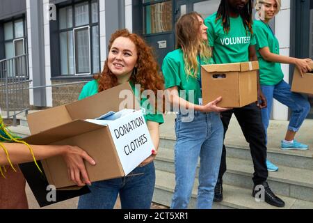 interracial group of volunteers working on humanitarian aid project, outdoors. mixed race friendly people working in charitable foundation, hold boxes Stock Photo