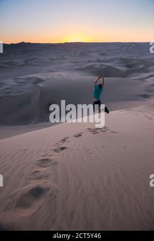 Tourist jumping in the desert at sunset at Huacachina, Ica Region, Peru, South America Stock Photo