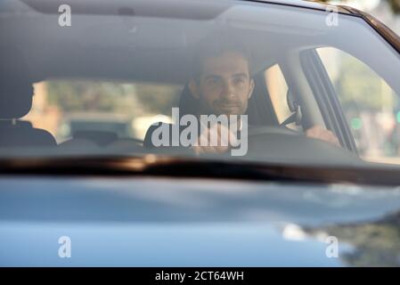 Young man driving his car to work in the city Stock Photo