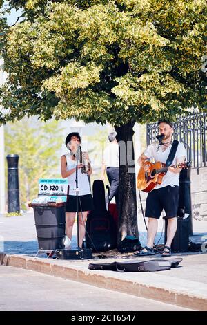 Montreal, Canada - June, 2018: Male and female street musicians playing guitar and saxophone and selling their cd in Montreal, Quebec, Canada. Stock Photo