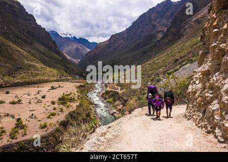 Porters hiking past Urubamba River in Sacred Valley on Inca Trail day 1, Cusco Region, Peru, South America Stock Photo