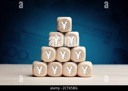 Chinese yuan or japanese yen symbol on wooden cubes against money background. Financial reserves, growth, profit, investment or savings in business co Stock Photo