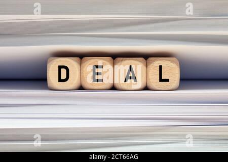 The word deal on wood cubes with file folder document background. Making a deal contract and paperwork in business concept. Stock Photo