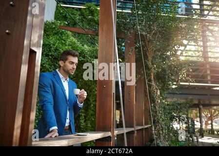Young businessman drinking an espresso outside at a cafe Stock Photo