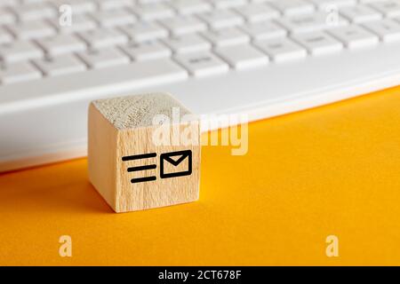 Email symbol on wooden block with computer keyboard background on yellow. Customer care, support or e-mail messaging concept. Stock Photo