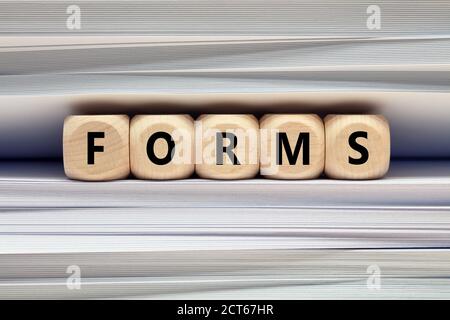 The word form on wooden cubes against paper and folder documents background. Filling form, paperwork and workload in business concept Stock Photo