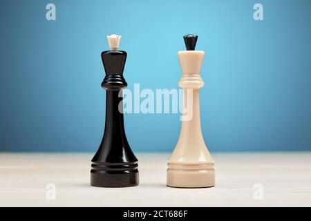 Black vs white chess king piece against blue background. Competition, confrontation or conflict in business strategy. Stock Photo