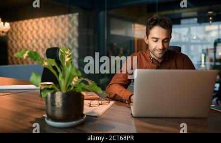 Businessman working after hours on a laptop in an office Stock Photo