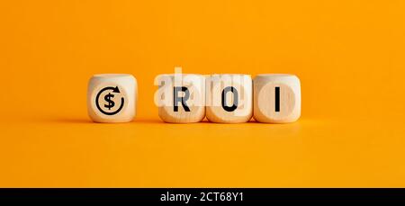 The word ROI return on investment written on wooden cubes with on yellow background. Profit or loss analysis in business and finance concept.