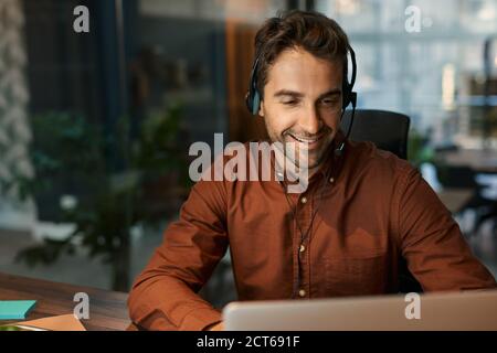 Smiling businessman talking on a headset with a client Stock Photo