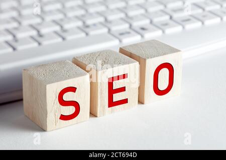 The word seo, search engine optimization written on wooden blocks with computer keyboard background. Stock Photo