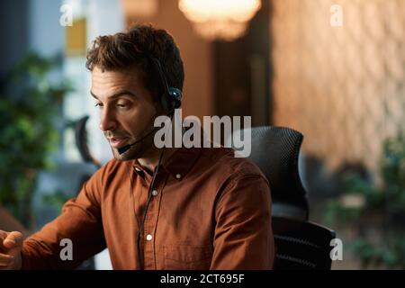 Businessman talking on a headset while working late Stock Photo