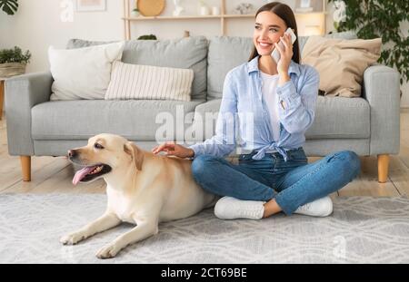 Portrait of young lady with her dog using mobile Stock Photo